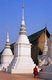 Thailand: A monk walks passed the smaller stupas surrounding the main chedi at Wat Suan Dok, Chiang Mai, northern Thailand